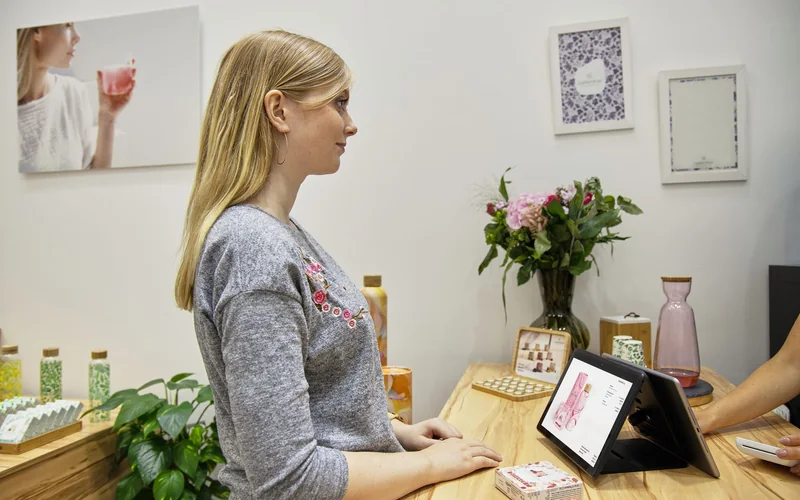 Cliente devant une tablette à l’accueil d’un salon